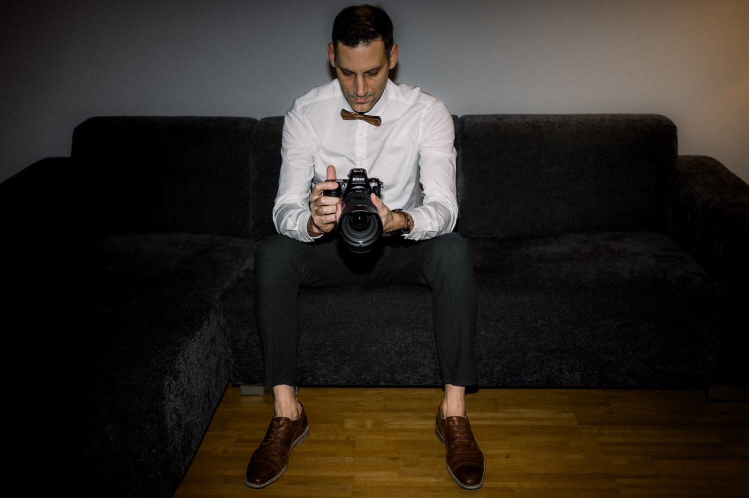 David Rickenbach, Hochzeitsfotograf aus Winterthur, sitzt mit Kamera auf einem Sofa – ruhiges, persönliches Portrait.