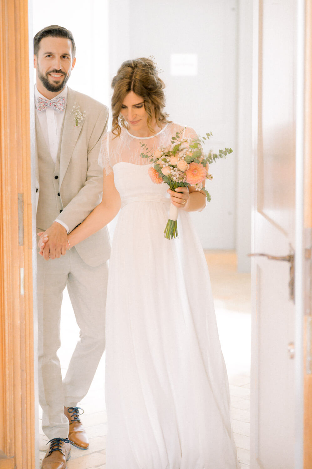 Brautpaar betritt gemeinsam einen hellen Raum während ihrer Hochzeit in ruhiger Bewegung