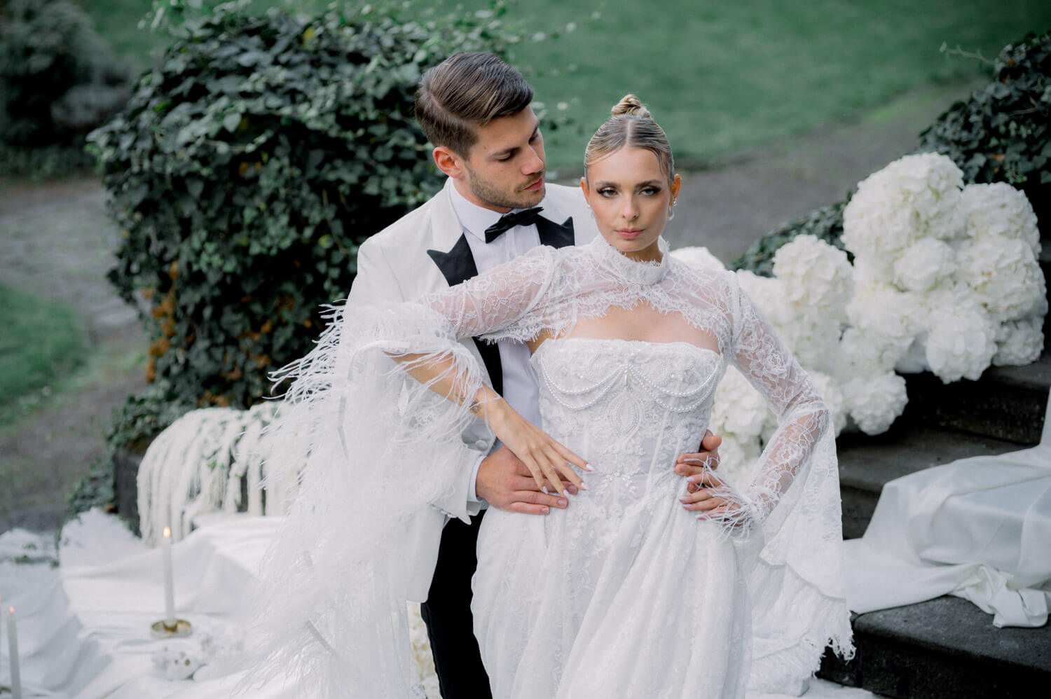 Brautpaar in enger Umarmung in einer eleganten Gartenkulisse