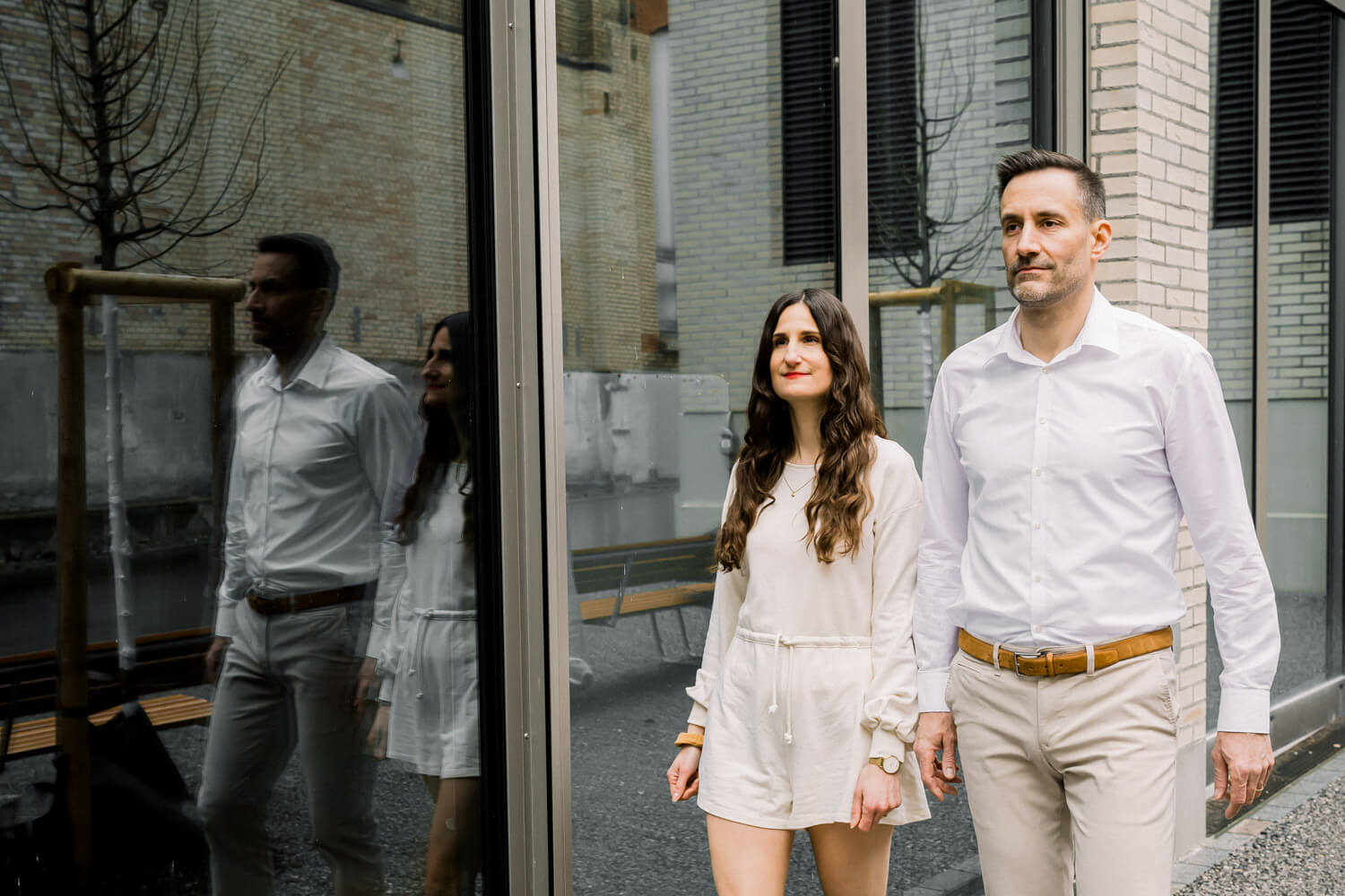 Paar läuft an moderner Glasfassade entlang mit Spiegelung in urbaner Umgebung in Winterthur
