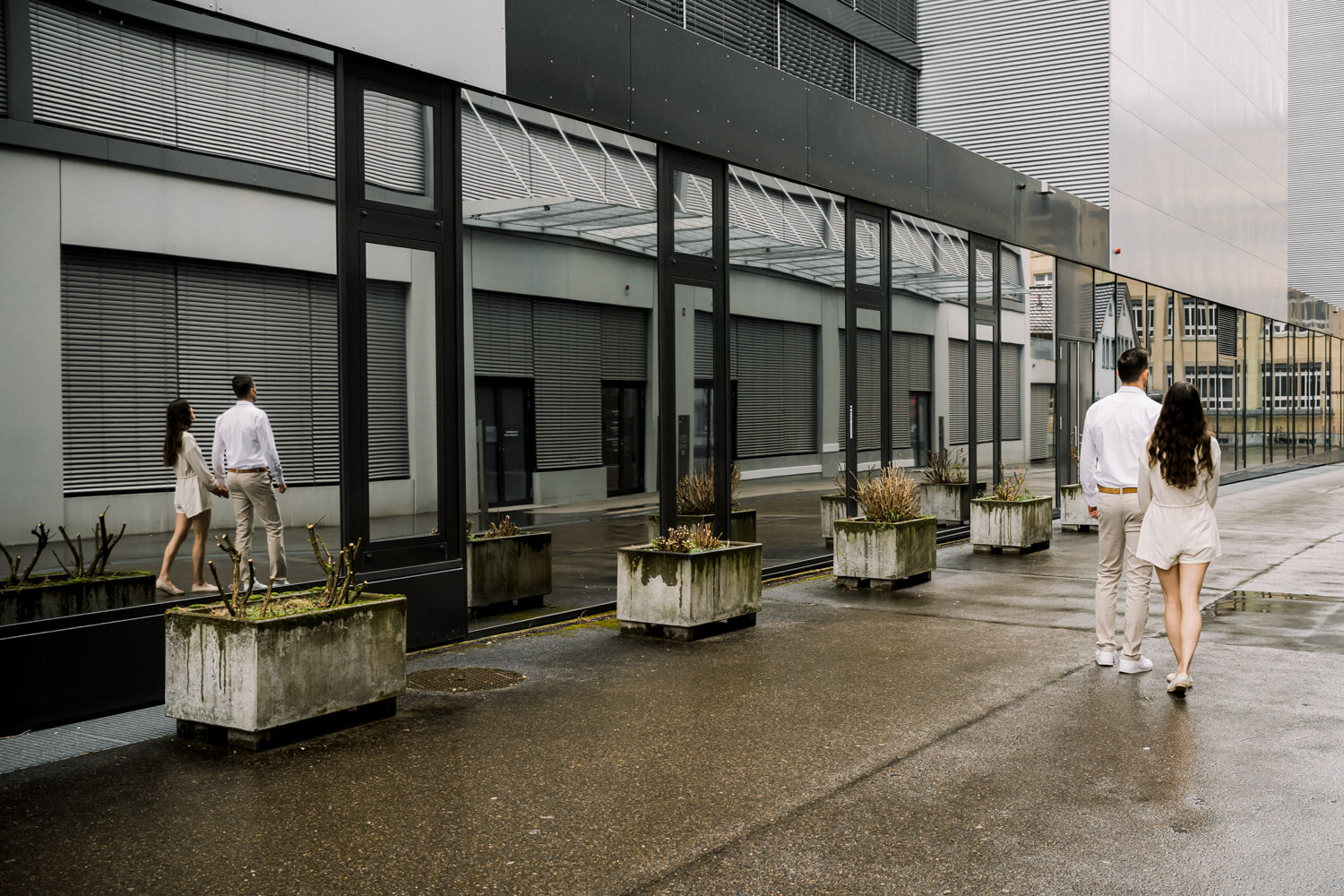 Paar spiegelt sich in Glasfront während es durch eine moderne urbane Umgebung läuft