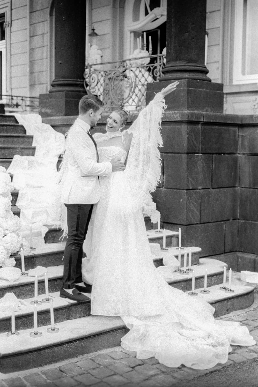Lachendes Brautpaar am Eingang einer prunkvollen Villa – Natürliche Hochzeitsfotografie
